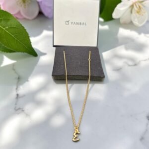 Collar Yanbal dorado con dije letra E, exhibido junto a su empaque original.