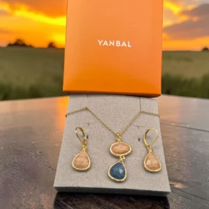 Collar y aretes Yanbal dorados con piedras rosa y azul, junto a su caja original.