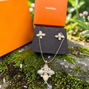 Collar y topitos Yanbal con dependiente floral y cristales sobre caja original naranja