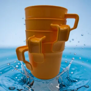 Set de cuatro vasos plásticos con asa color naranja, apilados sobre un fondo con salpicadura de agua.